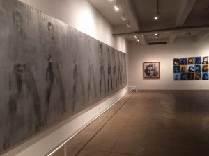 A massive panoramic painting with life-sized portraits of Elvis in black & white over silver paint